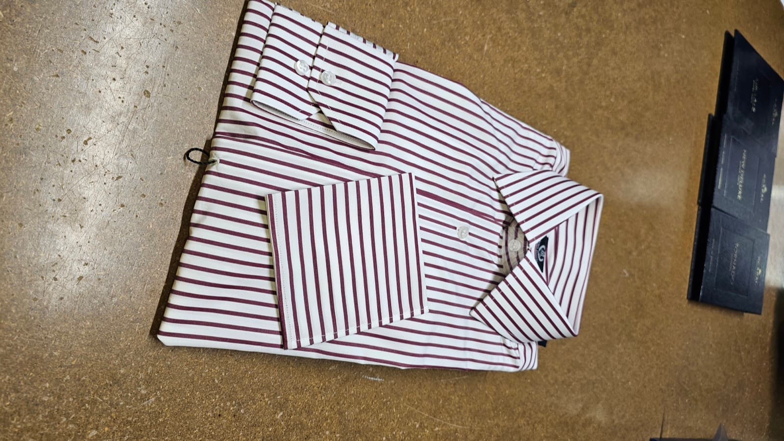 Burgundy striped shirt, folded, with cloth books behind