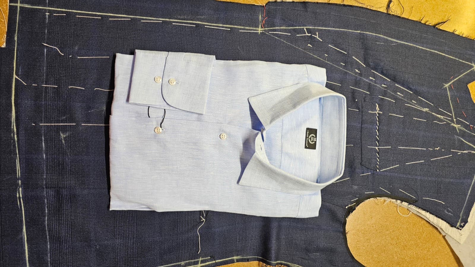 Pale blue linen shirt resting on a basted jacket in the workshop